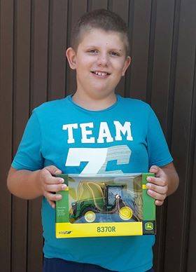 A képen Hegedűs Gábor Dániel látható a nyeremény John Deere játékmakettel a kezében.